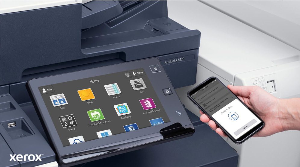 Xerox® ConnectKey®: mobiel printen en scannen Een close-up van de hand van een persoon die een smartphone vasthoudt, die draadloos is verbonden met het touchscreen-bedieningspaneel van een multifunctionele Xerox-printer. Hierop zijn de naadloze mobiele print- en scanmogelijkheden van Xerox ConnectKey te zien.