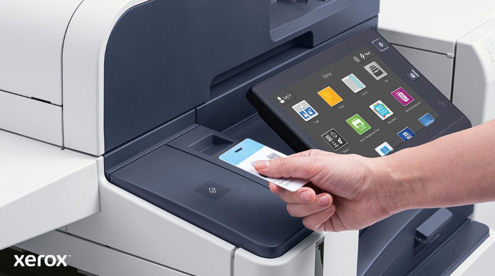 Een hand houdt een beveiligingspas vast en scant deze bij de kaartlezer van een moderne multifunctionele Xerox-printer met een groot touchscreen-display waarop verschillende toepassingspictogrammen worden weergegeven.
